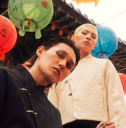 Two people in traditional hannovae Hanfu attire standing under colorful lanterns in a festive setting.