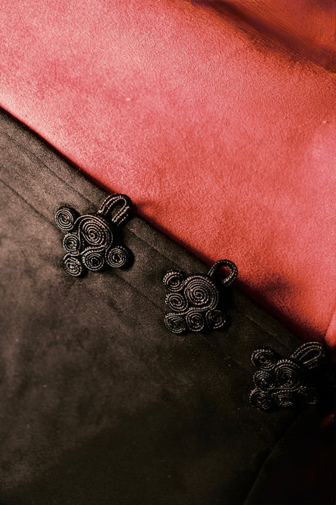 Black embroidered floral patterns on a dark fabric background