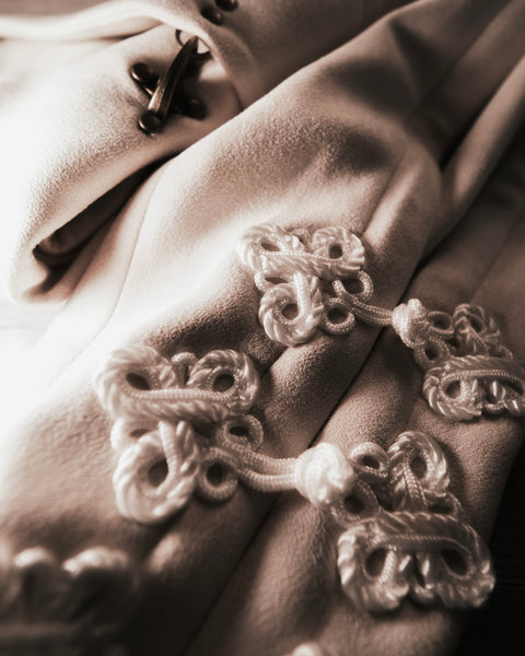 Close-up of a textured fabric with decorative buttons of DUne Hanfu Hannovae