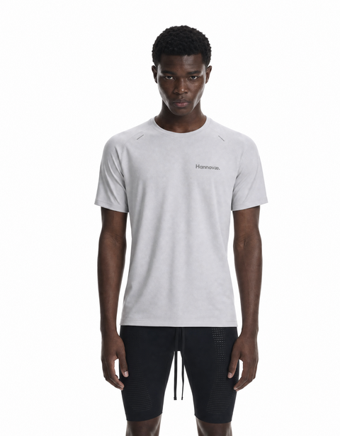A man modeling a light gray short-sleeve athletic t-shirt with a small 'Hannovae' logo on the left chest, paired with black athletic shorts, against a plain white background.