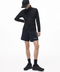 A model wearing a black long-sleeve athletic jacket, black running shorts with white side stripes, a black cap, black socks, and black trail running shoes, photographed against a solid white studio background.