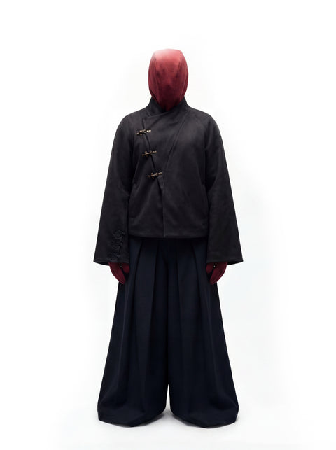 A person wearing a Hannovae Noire Hanfu jacket  wearing a white pair of trousers and red mask