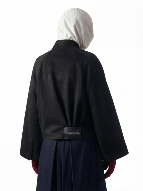 Person wearing a black hannovaecoat with a visible brand label on a white background